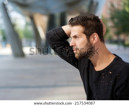Close up side view portrait of a male fashion model posing with hand in hair