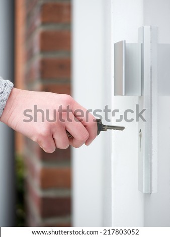 Side view female hand holding key to insert in door lock