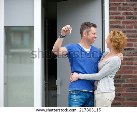 Portrait of a happy couple standing outside new home with keys