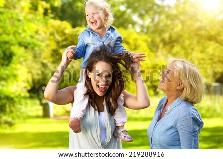 Portrait of a happy mother with child and grandmother having fun outdoors