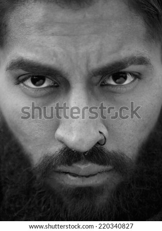 Close up black and white portrait of man with beard and nose piercing