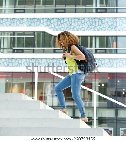 Portrait of a happy female student walking on campus with backpack