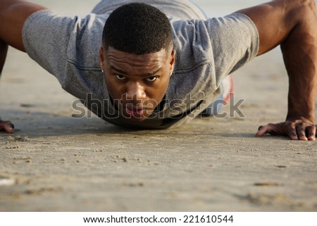 Close up portrait of a young man doing push ups outdoors