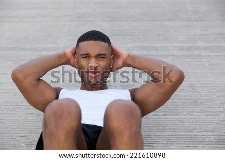 Close up portrait of a young man exercising doing sit ups outside