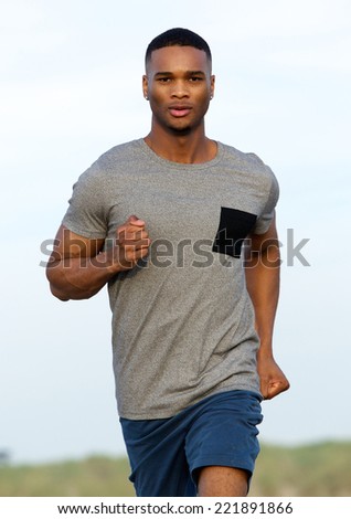 Handsome young man keeping fit by jogging outdoors