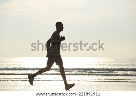 Side view of an african american man running on beach
