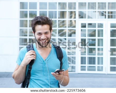 Close up portrait of a smiling young man with mobile phone and backpack