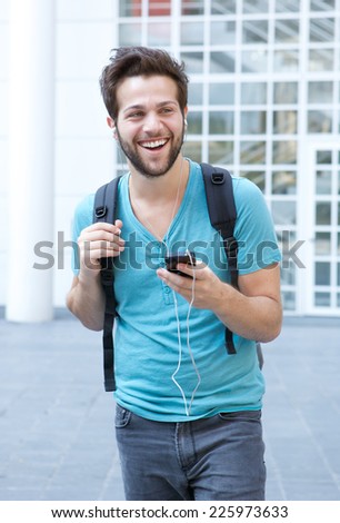 Portrait of a cool guy walking in the city with mobile phone and earphones
