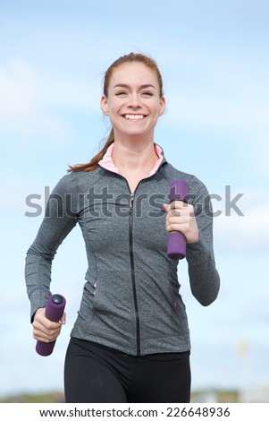 Healthy young woman walking with weights in hands