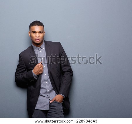 Portrait of a cool african american man with black business jacket posing on gray background