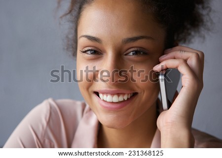 Close up portrait of a beautiful black woman smiling with mobile phone