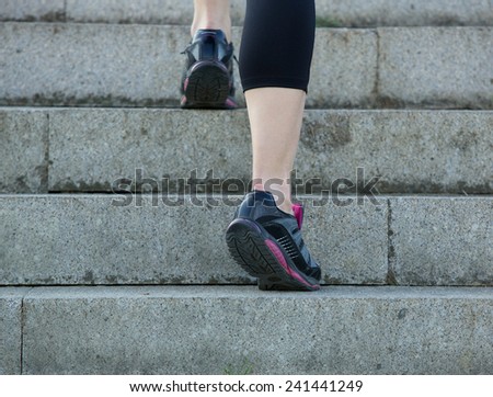 Low angle rear view young sports woman walking upstairs in gym shoes
