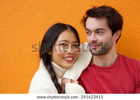 Close up portrait of a young man and woman posing against orange background