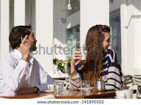 Portrait of a young couple sitting at outdoor cafe asking for the bill