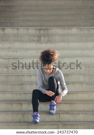 Full length portrait of a young sports woman tying shoelaces on steps