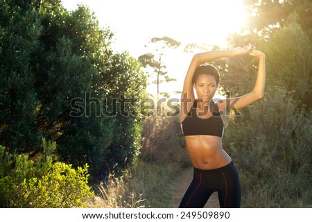 Portrait of a beautiful female fitness sports model stretching outdoors