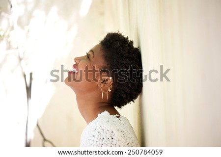Close up side portrait of a young black woman smiling and looking up
