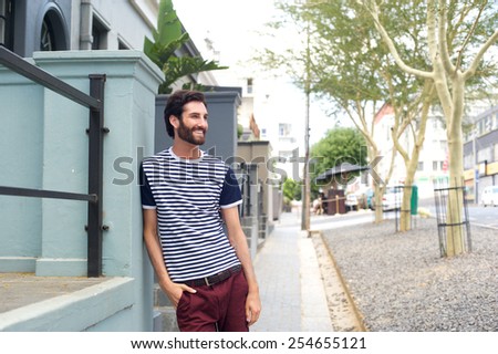 Portrait of a relaxed smiling man leaning on wall outdoors