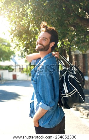 Portrait of a happy man walking away with travel bag