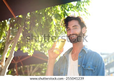 Cool guy drinking beer in summer at outdoor bar