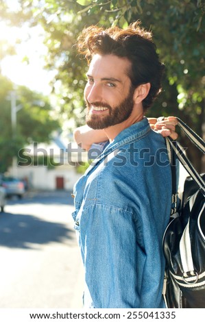 Portrait of a smiling man walking away with bag