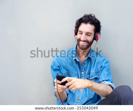 Portrait of an attractive young modern man smiling with mobile phone and headphones