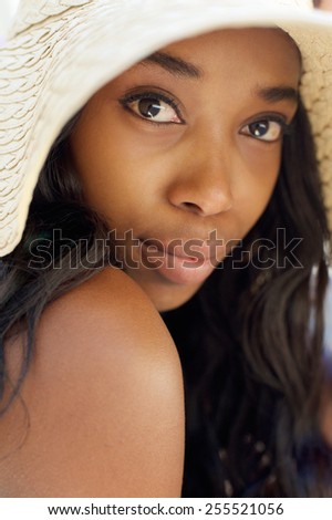 Close up portrait of an elegant young african american woman with long hair and sun hat