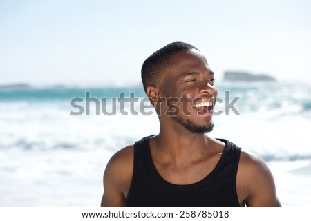 Close up portrait of a handsome young african american man laughing at the beach