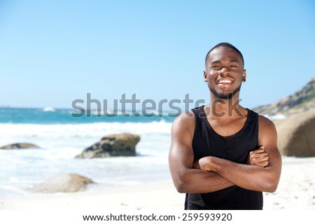 Portrait of a cool young guy smiling at the beach in summer