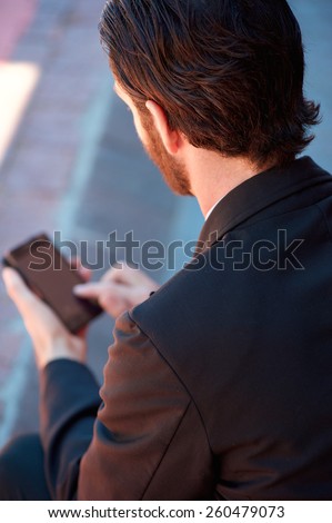 Portrait from behind of a young businessman holding mobile phone