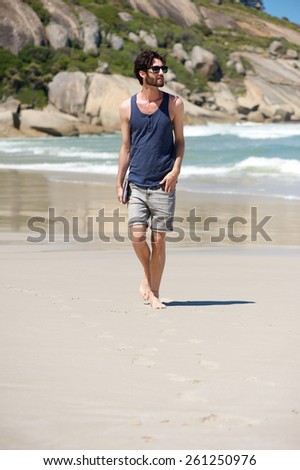 Full body happy man on vacation walking on isolated beach