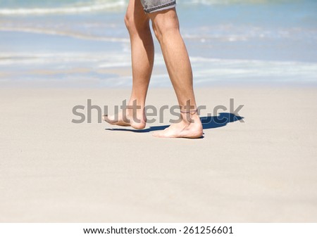 Close up man walking barefoot on white sand beach