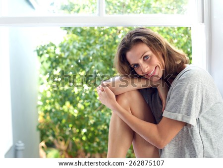 Portrait of an attractive woman smiling by window at home