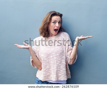 Portrait of a beautiful mid adult woman with hands raised in confusion