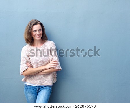 Portrait of a smiling mid adult woman standing with arms crossed on blue background