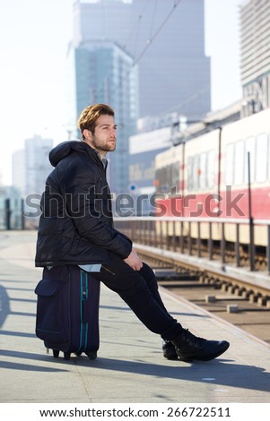 Portrait of an attractive young man sitting and waiting for train at station