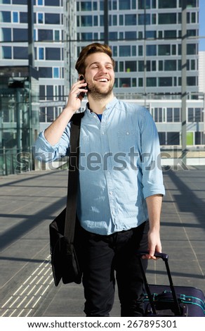 Portrait of a happy man walking with mobile phone at airport