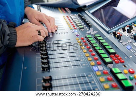 Man operating sound levels on audio mixer