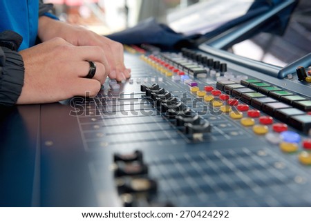 Man operating studio audio mixer with sound levels