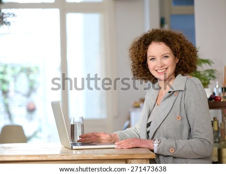Portrait of a happy middle aged woman using laptop at home