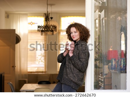 Portrait of an attractive middle aged woman standing with cup of tea at home