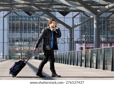 Portrait of an attractive man walking with suitcase and mobile phone at airport