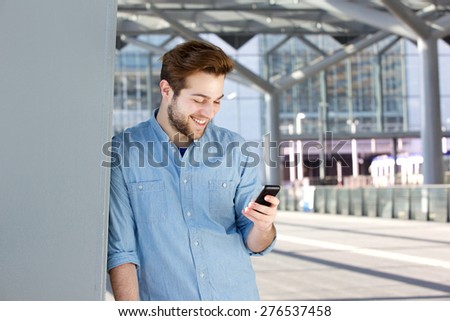 Close up portrait of a smiling young man looking at mobile phone