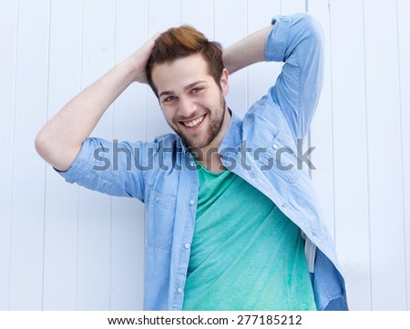 Portrait of a cool fashionable guy smiling with hands in hair