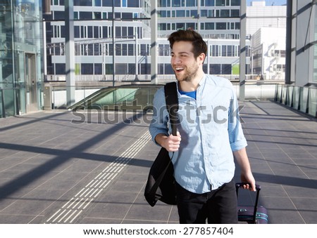 Portrait of a happy young man walking with bags at station