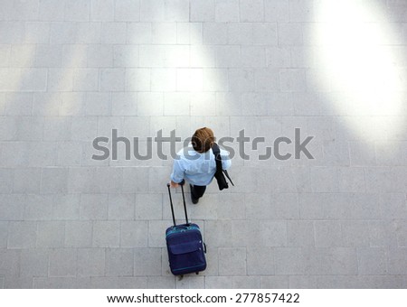 Portrait from above of a young man walking with luggage at station