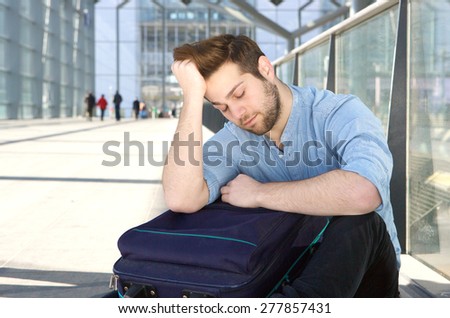 Portrait of a tired man with bag sleeping at airport