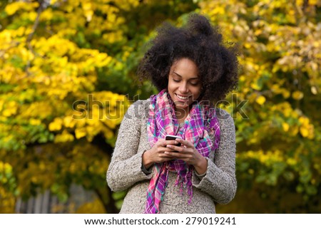 Portrait of a happy young woman reading text message on mobile phone