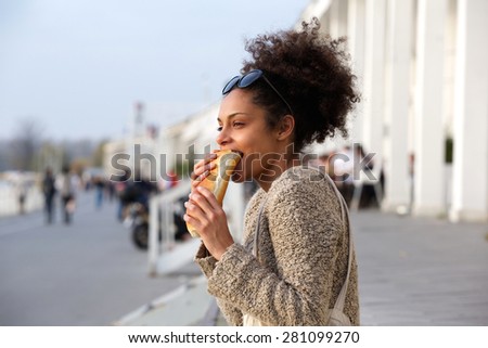 Side view portrait of a young woman eating junk food