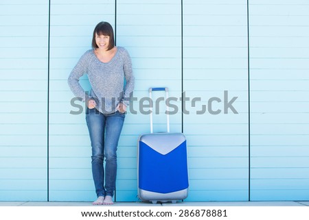 Full body portrait of an older woman smiling with suitcase